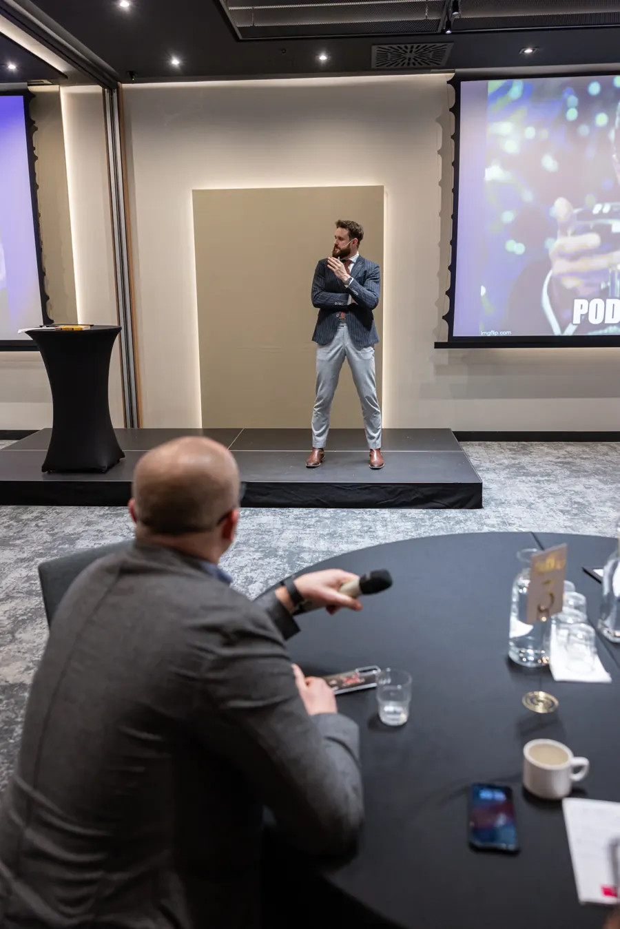 Warsztat na sali: prowadzący na scenie, uczestnik z mikrofonem przy stoliku